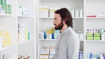 Patient grabbing pills from shelf at medical retail drug store to take care of his health and wellbeing. Man looking for his medicine on pharmacy shelves to treat his flu sickness at chemist shop