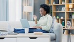 Happy black woman waving while using a laptop to make a video call in the living room. Young african american female excited to have a casual chat with friends or family at home during lockdown
