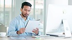 Financial manager or investment banker working at his desk inside a modern office. Young and focused male worker looking busy, typing data into an online system on a computer for client information