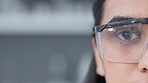 Half face of a female biologist in safety glasses with copy space. Closeup portrait of a scientist or medical expert looking at the camera with a serious and concerned expression aware of the risks