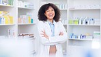 Happy and confident African American female chemist standing in front of her medicine shelves. Expert in white coat crossing arms and laughing with joy. Pharmacist pleased with her business turnover