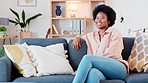 Laughing afro woman relaxing on sofa in home living room as new property homeowner or real estate investor. Portrait of confident, smiling and ambitious lady enjoying couch comfort in purchased house