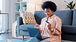 Woman cheering while shopping online for bargains and sales with laptop and credit card at home. Excited consumer and happy shopper saving on awesome deals and discount bookings while spending money
