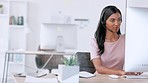Portrait of confident call center agent wearing headset and sending email in modern office. Young professional woman tracking a package online while working in customer care. Manager assisting client