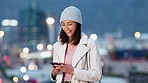 Woman reading funny text on her phone and laughing on a cold night in the urban city. Trendy and cheerful female sending a message or using a mobile app to book a cab or taxi to travel from town