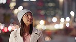 Tourist taking a photo on a phone while exploring a city alone at night. Young woman enjoying nightlife downtown against a background of blurry lights and bokeh. Female travelling and taking selfies