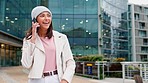 Stylish and happy woman walking outdoors talking on the phone in the city. A young, edgy, and confident female speaking on a call with her friend. A trendy lady enjoying her weekend in town