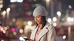 Trendy nightlife vlogger holding her phone and taking a photo of the city lights. Young woman admiring beautiful urban town, makes a video of the vibrant street view to share on her social media app