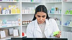 Focused pharmacist standing behind pharmacy counter taking notes on a computer, selling medicine to sick patients. Female doctor concentrating, typing a medicine prescription or dosage instructions.