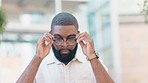 A stylish male student wearing glasses outdoors in the city. A confident trendy entrepreneur with a beard standing outside in an urban town. Portrait of smart and confident black man with spectacles