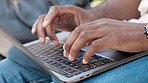 Closeup of a man typing on a laptop keyboard in the city outside. Hands of a student browsing the internet while doing research and planning for a course. Freelancer and entrepreneur working remotely