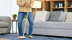 Man having fun and dancing with a broom while sweeping and cleaning the living room at home alone. One carefree person doing dance moves and being silly while doing housework and chores in the lounge