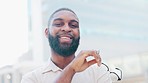 Portrait of African in finance with beard smiling outside holding reading glasses with blurred background. Financial accountant is happy after checking the tax and business profits of the company