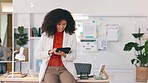 Cheerful, smiling and happy black business woman browsing on a digital tablet in a modern office. Portrait of confident entrepreneur feeling ambitious and motivated for success while planning online