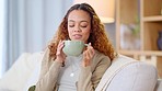 Woman drinking a hot cup of tea or coffee at home. Carefree, relaxed and cheerful young female smelling the aroma of a fresh warm beverage while taking a sip and enjoying a comfortable break at home