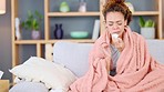 Sick woman suffering from flu while lying on a sofa at home. Young female feeling unwell, shivering with a fever while recovering from Covid19 in a living room. Taking off from work to treat illness