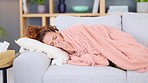 Sick woman resting with a cold or flu on the couch at home alone. Black female coughing, looking restless, and trying to sleep while lying on the sofa in the living room. Girl recovering from covid