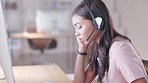 Young call center agent suffering from a headache or migraine while working in customer service. Support employee feeling tired, overworked and sick while wearing a headset at her desk in the office