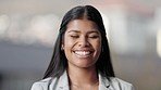 Closeup portrait of a real estate agent smiling and looking cheerful while standing against a blurred background alone. The face of one happy and joyful young realtor laughing while selling houses