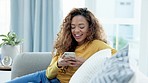Trendy girl laughing, watching video on her phone and eating popcorn. Entertained young woman watching funny series, movies or shorts on social media and snacking while enjoying her weekend free time