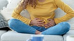 Closeup of a woman with period cramps rubbing her stomach. Young girl suffering from endometriosis and experiencing discomfort, painful belly. A stomachache due to PMS or menstruation cycle