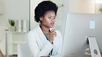Human resource manager thinking, using a computer to review employee contracts and plan office schedules. Serious, confident hiring boss with afro using technology to innovate team building exercises