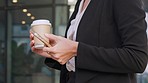 Business woman texting on a phone and drinking coffee in a city. Closeup on hands of a corporate professional browsing social media and searching the web online while commuting and traveling in town
