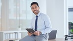 Successful young business man laughing while browsing on a tablet in the office. Portrait of a confident male corporate professional feeling positive after completing a deal or finishing a task