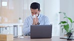 A modern business man feeling sick with covid fatigue while working online at a desk on his laptop. Closeup of an male corporate manager blowing his nose. An ill office worker frustrated at work.