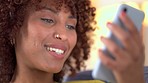 Face of a woman talking on a video call while sitting on the couch alone at home looking cheerful. Happy african female with curly hair smiling and chatting to friends or family inside being social