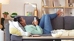 Carefree woman texting and typing a message online to her friends while relaxing alone on the couch at home. One happy and relaxed female scrolling through social media and searching the internet