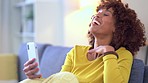 Cheerful woman talking on a video call and laughing while relaxing on the couch at home. Trendy afro female having fun while having a funny conversation on the phone with a distance friend or family 