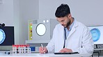 Medical science lab assistant working on new medicine drug. A young microbiologist, scientist or health professional man wearing a white coat writes research results on paper and smiles at the camera