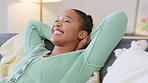 Happy black woman enjoying the freedom to relax on a sofa at home. Carefree African American female laughing while lying back, stressless and content. Lady with no worries enjoying a day indoors