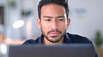 Focused business man concentrating on a task or project in his office at work. Young male entrepreneur reading an email and typing a reply while working to meet a deadline and thinking of a solution