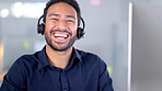 Laughing call centre agent helping customers while wearing a headset and typing on a computer to answer questions. Portrait of a friendly and cheerful male customer service operator in his office