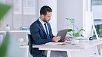 Businessman using digital tablet, typing on computer keyboard and planning global business strategy. Confident professional sitting alone in office, multitasking and using technology to innovate idea