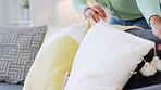 Closeup of interior designer using sofa and couch cushions or pillows to stage real estate house for selling. A woman touching and neatly arranging decorations in routine housekeeping and home chores