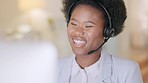 Happy black call center agent wearing a headset and working in a modern office. Young African American woman talking on a video conference. Female smiling while working in customer care