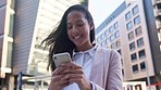 Young woman getting good news on a phone against an urban background. Excited female texting about a successful interview for a new job. Lady smiling while reading an email about a promotion 