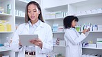 Pharmacist with digital tablet while doing stock update and counting inventory with a colleague in a pharmacy. Female chemist typing on device and searching pharma app or checking online prescription