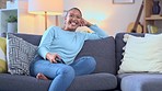 Woman laughing while watching a funny tv series on a couch at home. Happy female sitting in front of television to enjoy a weekend of hilarious entertainment. Streaming comedy movies and sitcom shows