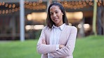 Portrait of public relations officer with her arms folded, ready to share news or broadcast to live press. Proud, smiling professional standing alone in a city with arms crossed and bokeh background