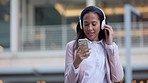 Funky woman using a phone and listening to music on headphones while walking through city alone. Cool, fashionable and stylish student selecting and choosing songs from playlist on technology in city