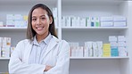 Portrait of a pharmacist with crossed arms against a background of prescription medication on shelves. Professional healthcare worker waiting to diagnose and prescribe pills at a clinic or drugstore