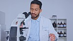 Closeup of young male professional scientist running tests. Happy, smiling man conducting new research and science for new discoveries. Guy finding solutions and documenting them in a lab.