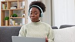 A confident, professional and casual business woman wearing headphones talking on a video call while working from home. Social female on laptop explains something to a friend, client or colleague.