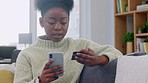 Young woman online shopping at home on sofa. Female adult remote banking for items, purchasing merchandise. Lady on a phone providing bank details to complete transaction.