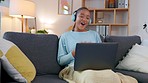 Casual lady female having a funny conversation on an online video call with a loved one, talking using headphones and a laptop. Laughing woman chatting to a friend on social media sitting on a sofa.