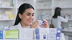 Smiling female pharmacy student working with store stock. Laughing healthcare professional looking at medicine. Young doctor excited about medical profession and helping people find a covid cure. 